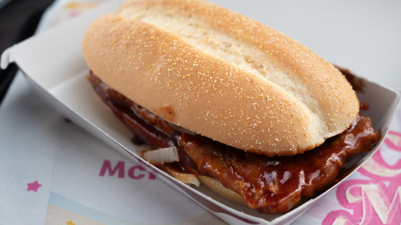 A McRib in a paper tray on a table