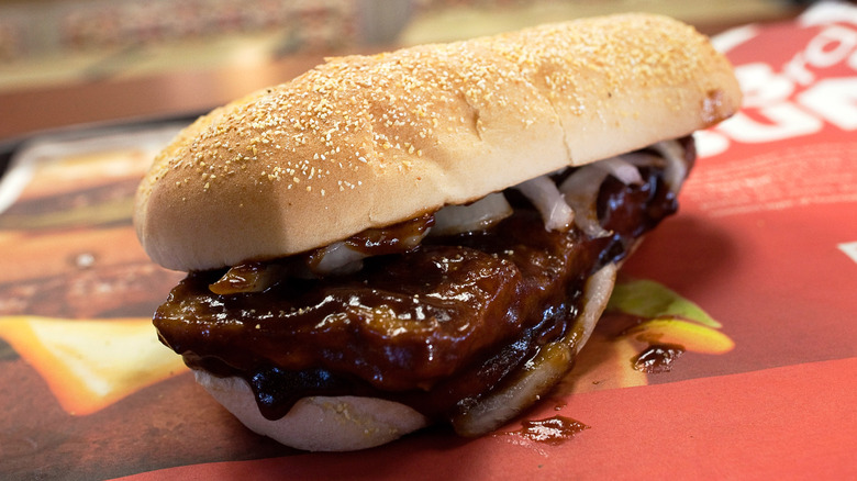 A saucy McRib with onions on a table with red paper