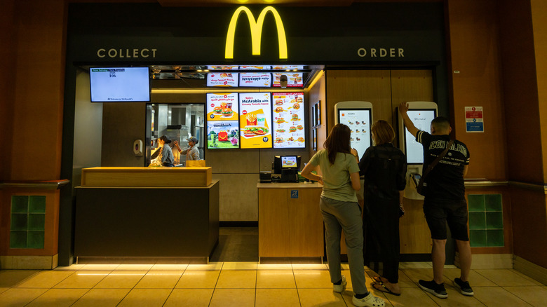 Three people at a McDonald's ordering from the screens