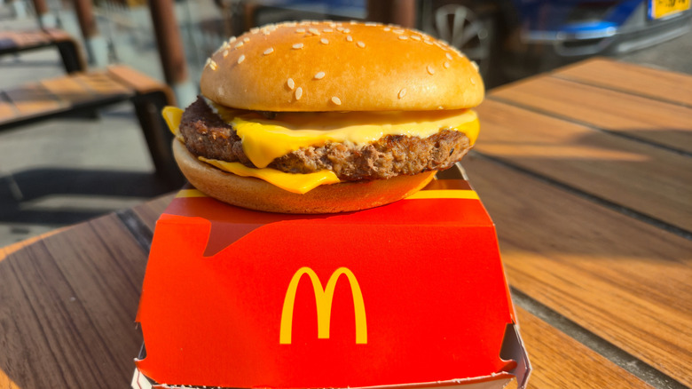 a quarter pounder with cheese sitting atop a red mcdonalds box