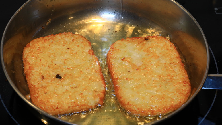 two hashbrowns being fried in oil in a pan