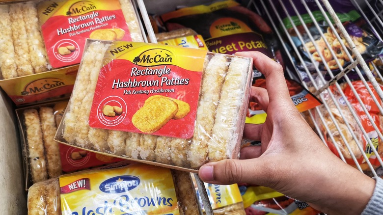 Hand picking up a Hash brown Patties frozen in the supermarket