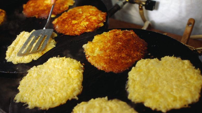 Hash browns lined up and being fried on a griddle