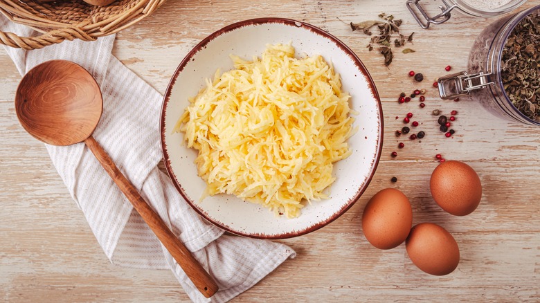Grated raw potatoes with eggs and seasoning for hashbrowns