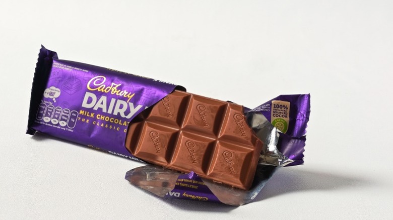 A partially unwrapped bar of Cadbury Dairy Milk Chocolate.