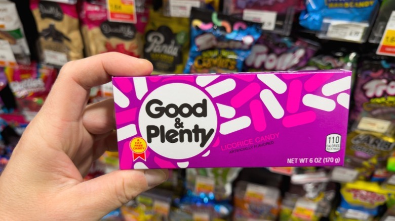 A hand holding a box of Good & Plenty.