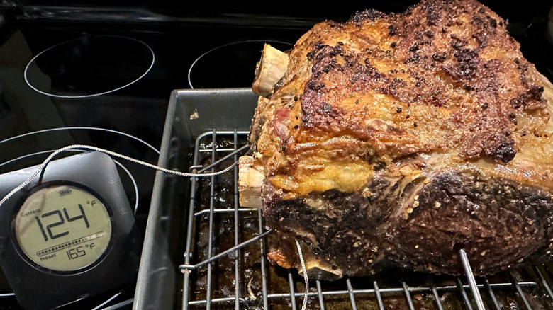 Cooked prime rib on a rack with a meat thermometer reading 124 degrees Fahrenheit