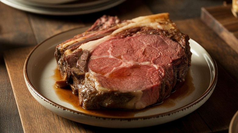 Slice of juicy medium rare prime rib with jus on a plate