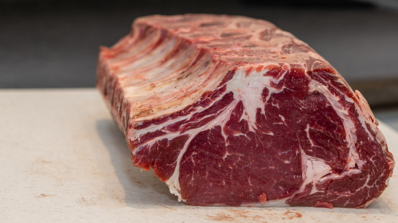A large raw prime rib beef roast on a white board