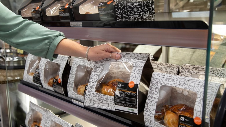 Publix rotisserie chickens in warmer with hand taking one