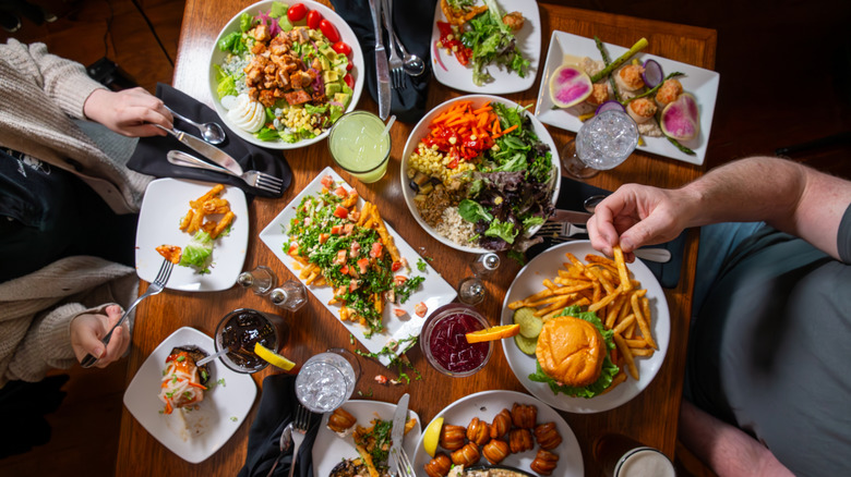 Top view of a restaurant table full of food including burgers and salad's
