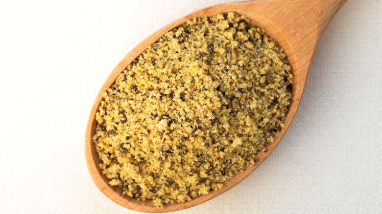 Lemon pepper seasoning on a wooden spoon.