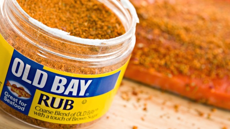 An open jar of Old Bay seasoning in front of a piece of salmon.