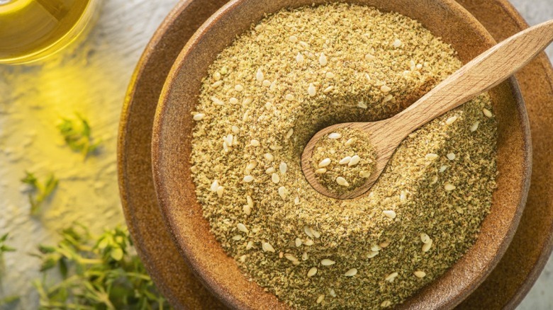 A wooden bowl of za'atar with a matching spoon.