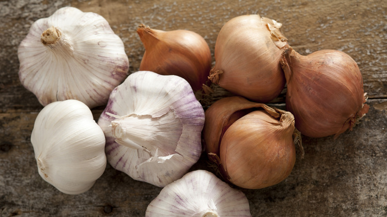 Whole heads of garlic and brown onions on a wood background
