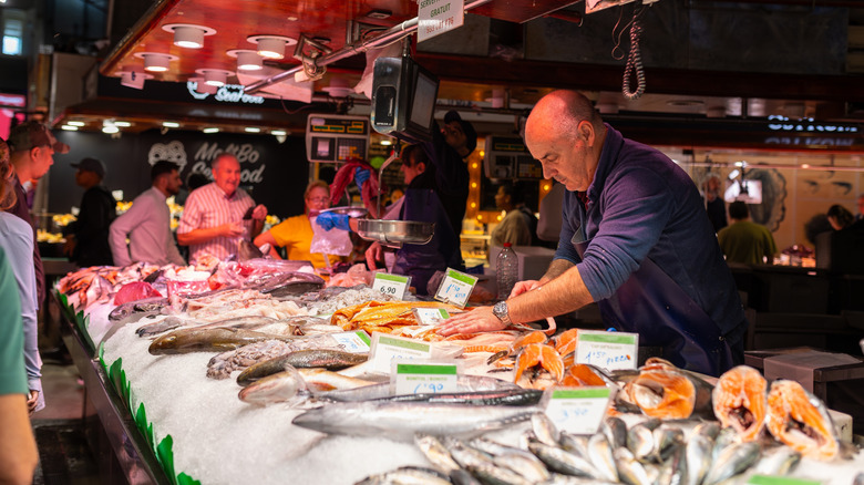 Fishmonger standing by market stall