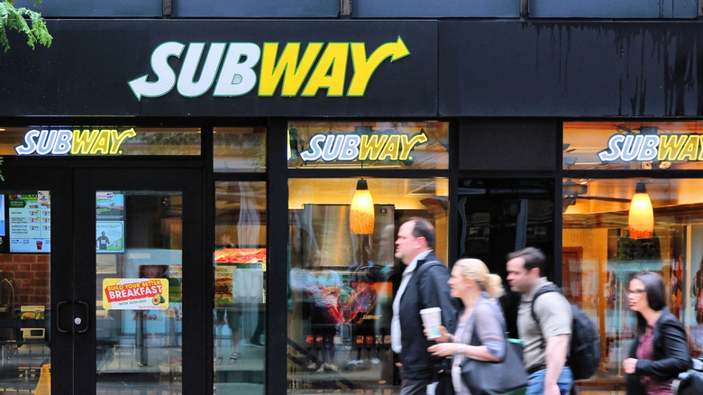 People walking in front of a Subway restaurant
