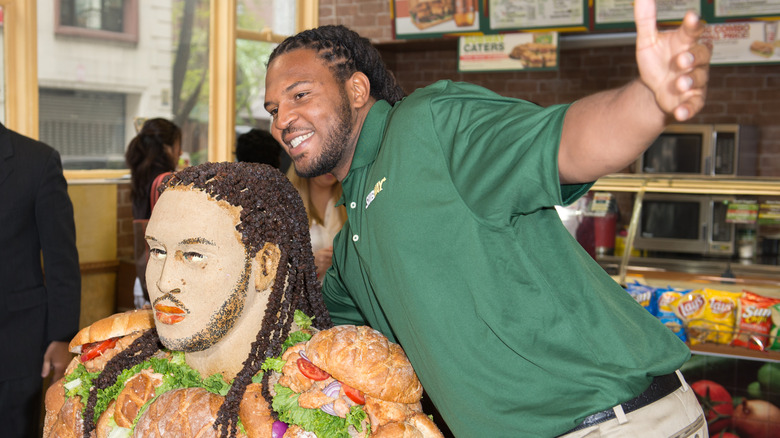 NFL player Jarvis Jones in front of a sandwich sculpture at a Subway in New York City