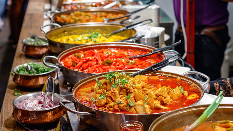 A buffet table of assorted Indian dishes in copper pots with condiments