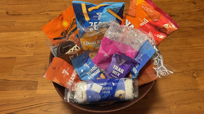A large variety of pre-packaged 7-Select snacks in a bowl on a wooden table
