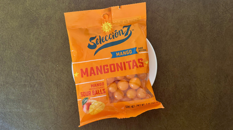 An orange package of mango sour balls on a small white plate