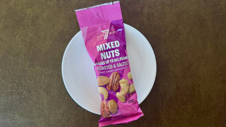 A purple package of 7-Select mixed nuts on a small plate