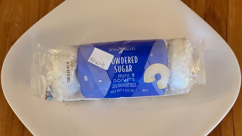 A package of 7-Select powdered sugar donuts on a square white plate