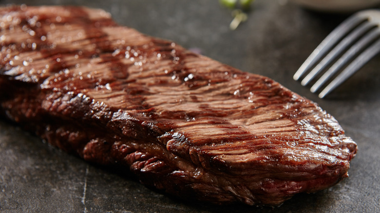 Whole grilled Denver steak next to a fork