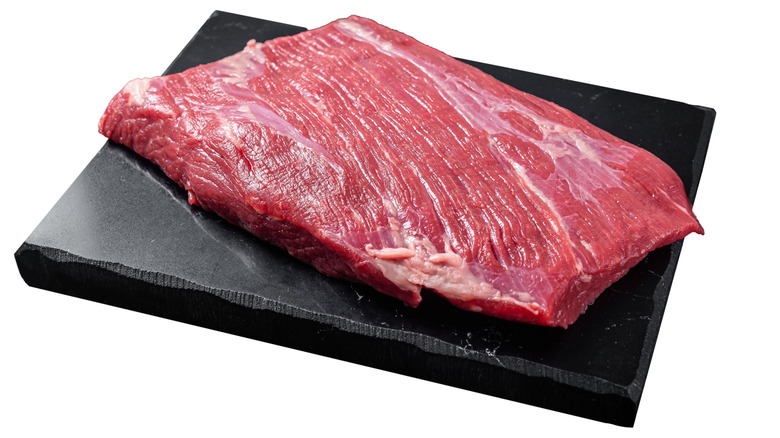 Raw flank steak on a slab