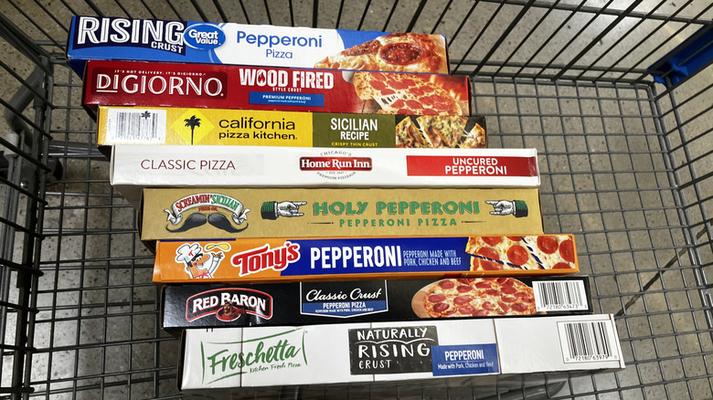 A stack of frozen pizza boxes arranged in a grocery shopping cart to show their spines.