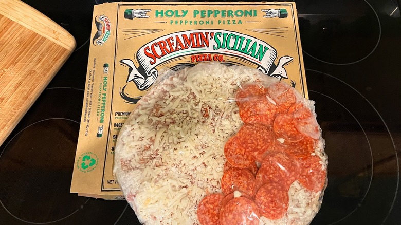 Frozen pepperoni pizza on top of Screamin' Sicilian pizza box.