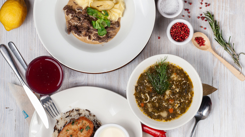 Top view of a three course set menu: beef stroganoff with mashed potatoes, roasted crunchy cutlet with rice and soup