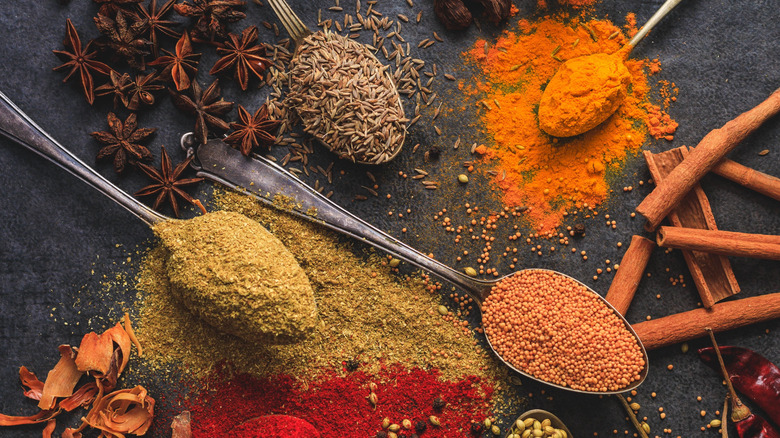 An array of whole spices against a stone background