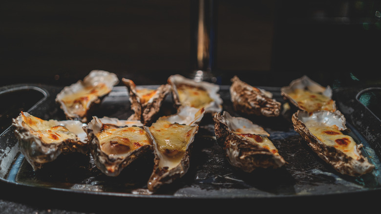 Oysters Rockefeller on a platter in a dimly lit room