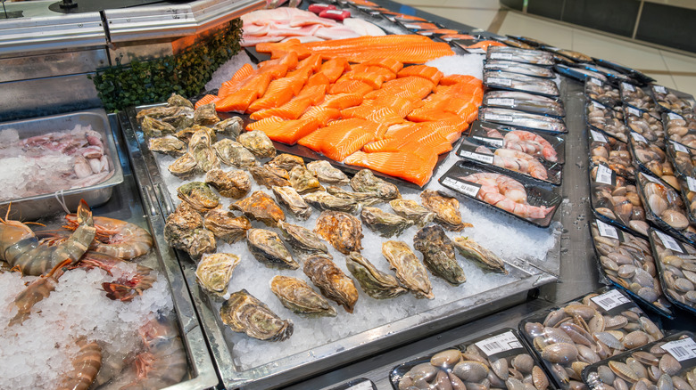 A raw seafood display including fresh oysters on ice at a grocery store