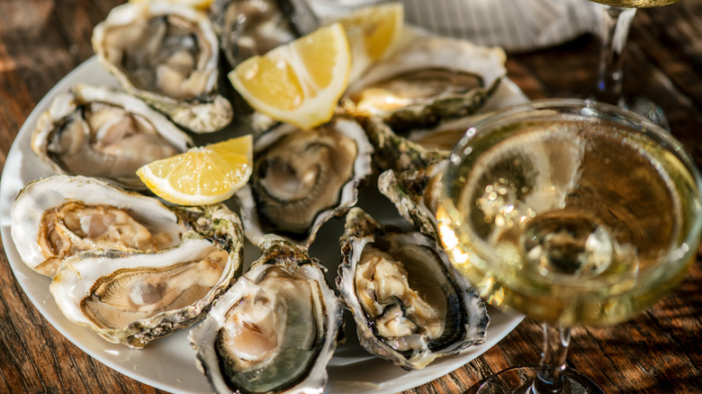 Close-up of a platter of oysters with lemon next to a glass of champagne