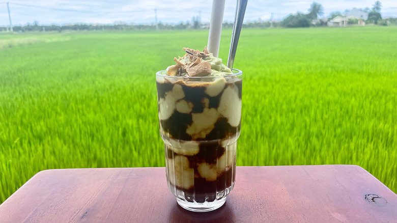 Avocado coffee on table overlooking lush green rice paddies