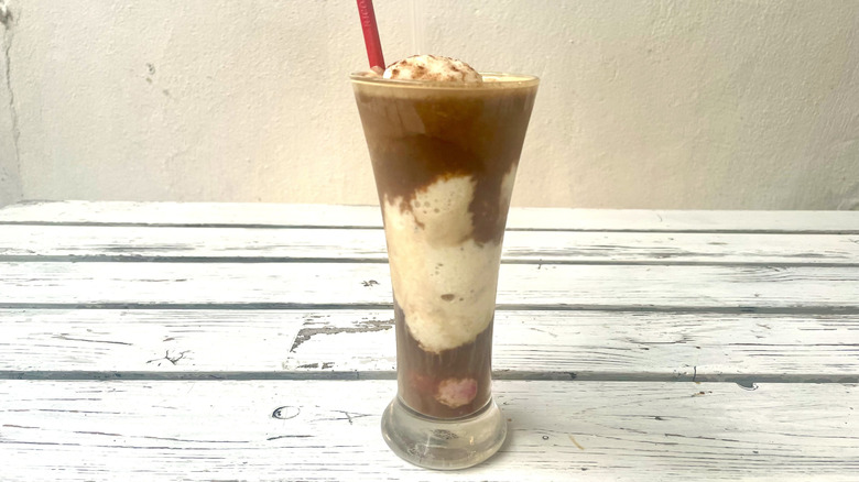 Banana coffee with red spoon sitting on white wooden table
