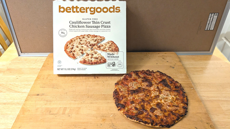 A freshly cooked bettergoods cauliflower crust chicken sausage pizza beside the box it came in