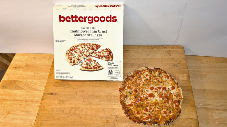 A freshly cooked bettergoods cauliflower crust Margherita pizza beside the box it came in