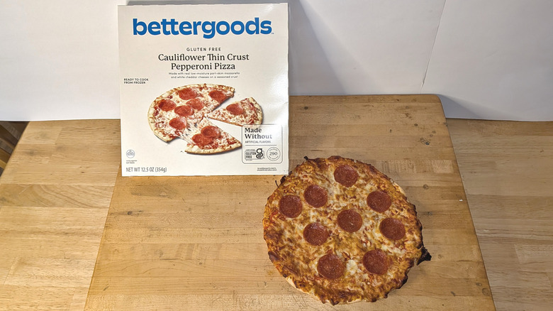 A freshly cooked bettergoods cauliflower crust pepperoni pizza beside the box it came in