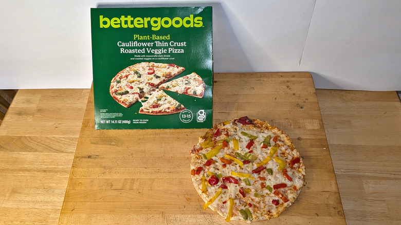 A freshly cooked bettergoods cauliflower crust roasted veggie pizza beside the box it came in