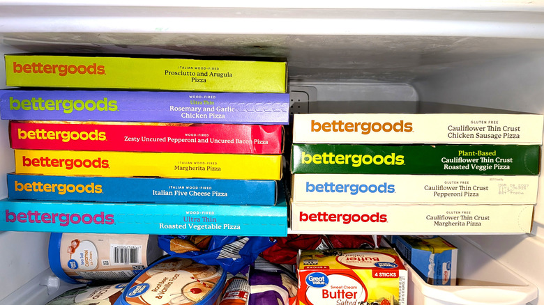 A stack of bettergoods frozen pizzas in a home freezer with products from Walmarts other private-label brand, Great Value
