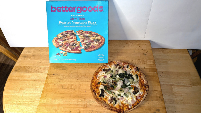 A freshly cooked bettergoods wood-fired ultra thin roasted vegetable pizza beside the box it came in