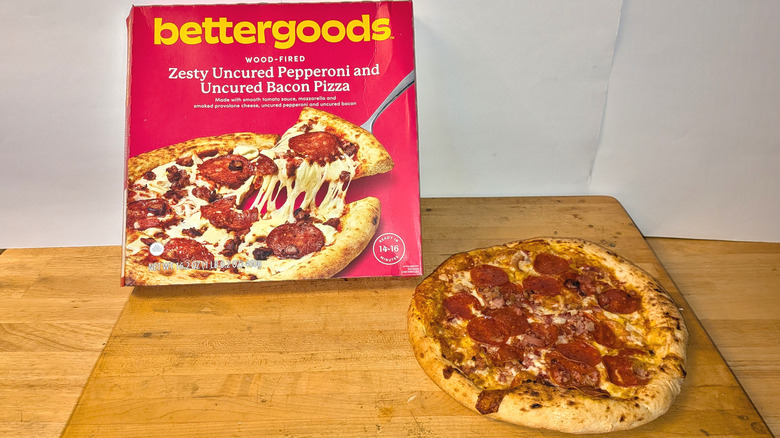 A freshly cooked bettergoods wood-fired zesty uncured pepperoni and uncured bacon pizza beside the box it came in