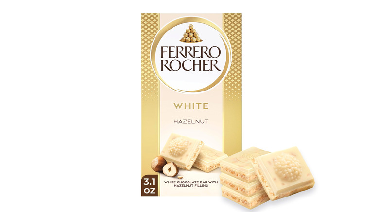 A Ferrero Rocher white chocolate bar shown alongside four squares of chocolate on a white background