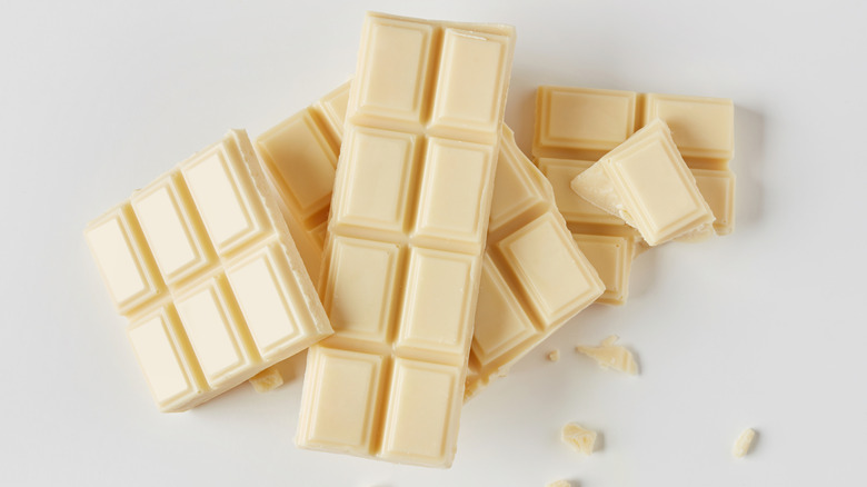 Top view of broken and whole white chocolate bars on white background