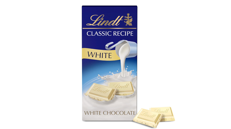Lindt White Chocolate Bar alongside two squares of chocolate on a white background
