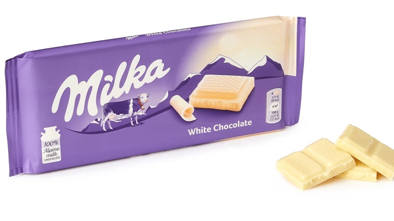 Wrapped Milk White Chocolate bar alongside squares of white chocolate on a white background