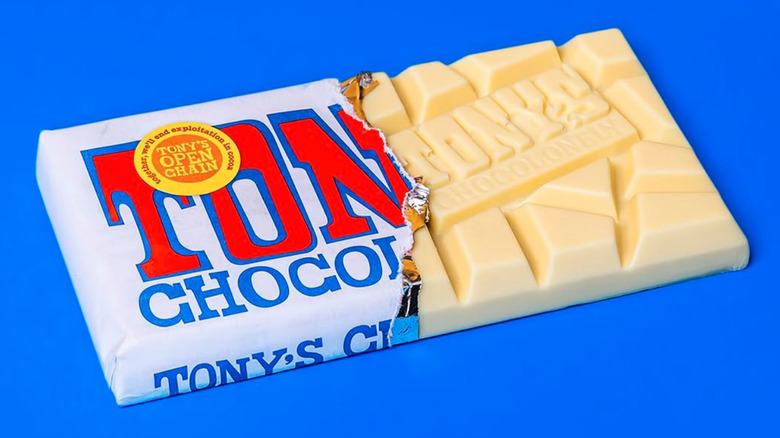 Tony's Chocolonely White Chocolate Bar with half of the wrapper removed on a blue baackground